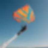 Kiteboarder soaring through the air with vibrant kite colors against a clear blue sky