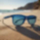 Stylish surf sunglasses with blue lenses on sandy beach