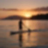 Sunset silhouette of paddle surfer on tranquil waters