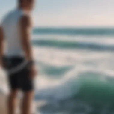 Person holding a white surf leash with ocean waves in the background