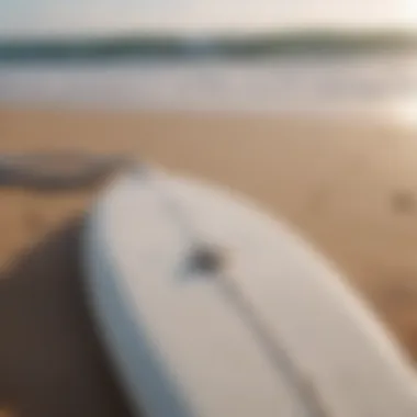 Surfboard with white surf leash attached on sandy beach